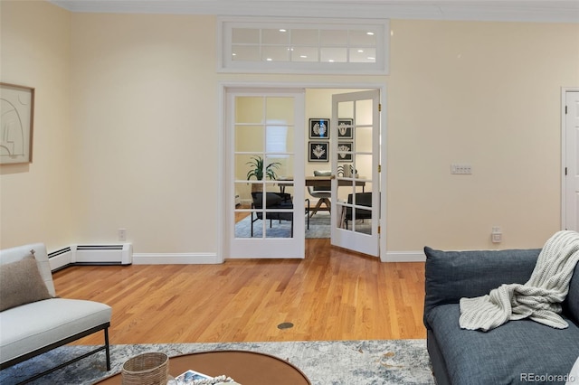 living room with baseboards, light wood finished floors, a baseboard radiator, and ornamental molding