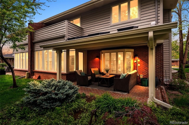 back of property featuring a balcony, an outdoor hangout area, and brick siding