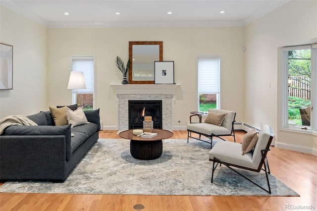 living room with wood finished floors, a baseboard radiator, a warm lit fireplace, crown molding, and recessed lighting