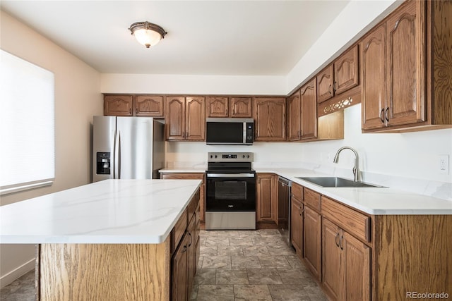 kitchen with a kitchen island, appliances with stainless steel finishes, brown cabinets, stone finish flooring, and a sink