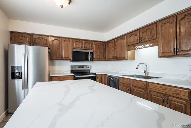 kitchen with stainless steel appliances, a sink, and light stone counters