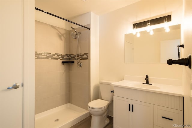 full bath with toilet, a tile shower, and vanity