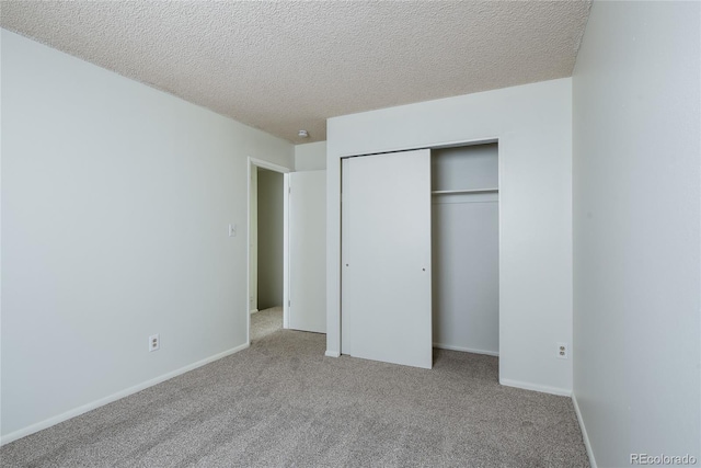 unfurnished bedroom featuring a closet, carpet flooring, a textured ceiling, and baseboards