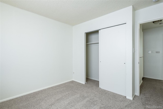 unfurnished bedroom featuring a textured ceiling, a closet, baseboards, and carpet flooring