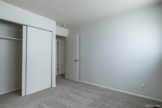 unfurnished bedroom featuring carpet floors, a closet, a textured ceiling, and baseboards