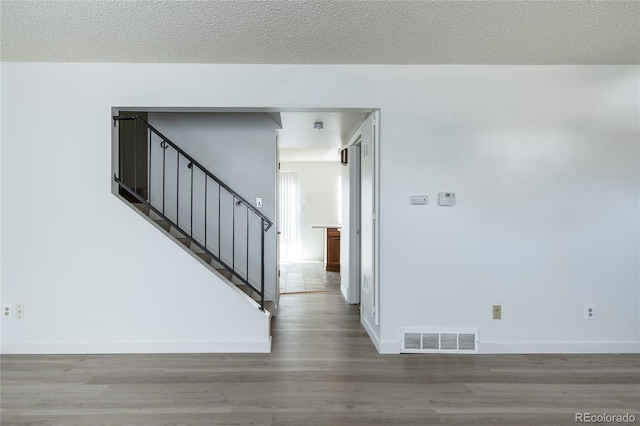 interior space with stairway, a textured ceiling, visible vents, and wood finished floors