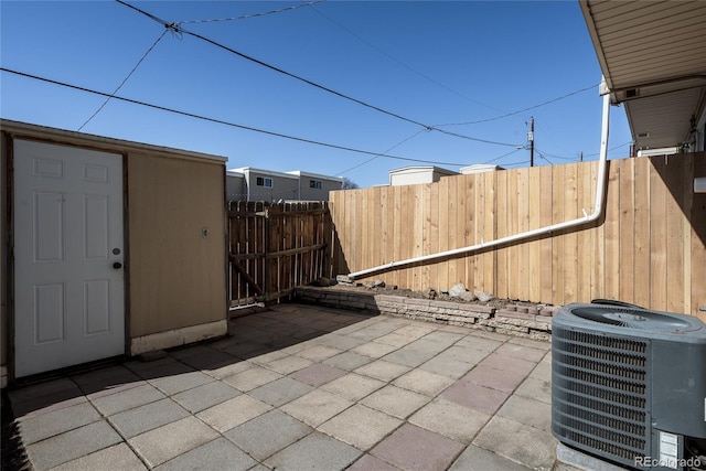 view of patio featuring fence, central AC unit, and an outbuilding