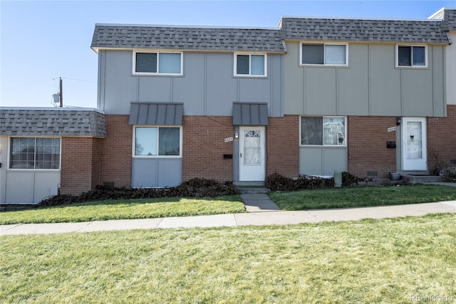 view of property featuring brick siding and a front yard