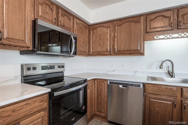 kitchen with stainless steel appliances, brown cabinetry, and a sink