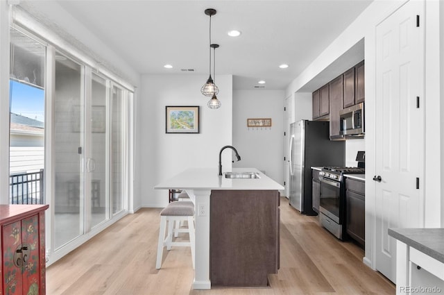 22826 E Tufts Pl Unit A, Aurora, CO 80015 - kitchen with appliances with stainless steel finishes, light wood finished floors, dark brown cabinetry, a center island with sink, and recessed lighting
