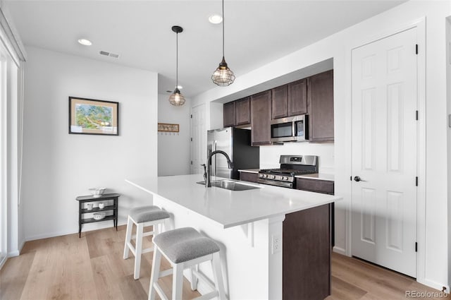 22826 E Tufts Pl Unit A, Aurora, CO 80015 - kitchen featuring stainless steel appliances, dark brown cabinetry, light wood-style flooring, a breakfast bar area, and an island with sink