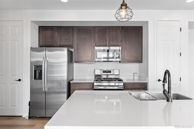 22826 E Tufts Pl Unit A, Aurora, CO 80015 - kitchen featuring appliances with stainless steel finishes, light countertops, dark brown cabinetry, pendant lighting, and light wood-style floors