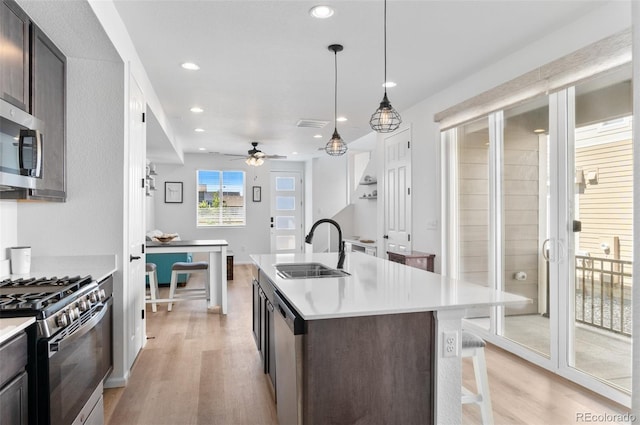 22826 E Tufts Pl Unit A, Aurora, CO 80015 - kitchen with appliances with stainless steel finishes, light wood-style floors, recessed lighting, light countertops, and a kitchen bar
