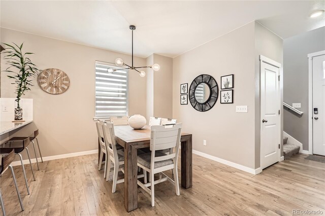 764 N Quatar St, Aurora, CO 80018 - dining room featuring light wood-type flooring, a chandelier, and stairway
