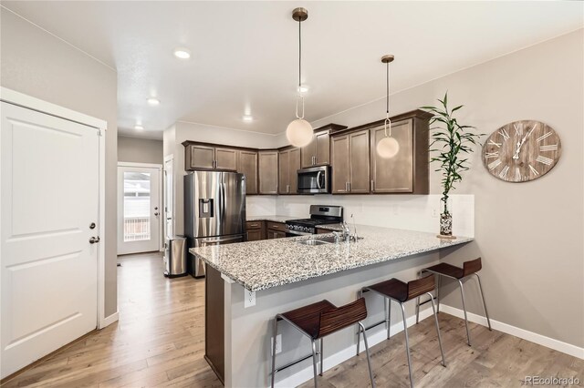 764 N Quatar St, Aurora, CO 80018 - kitchen featuring appliances with stainless steel finishes, a peninsula, light wood-style flooring, light stone counters, and recessed lighting