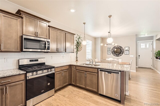 764 N Quatar St, Aurora, CO 80018 - kitchen with stainless steel appliances, a peninsula, tasteful backsplash, and light wood-style flooring