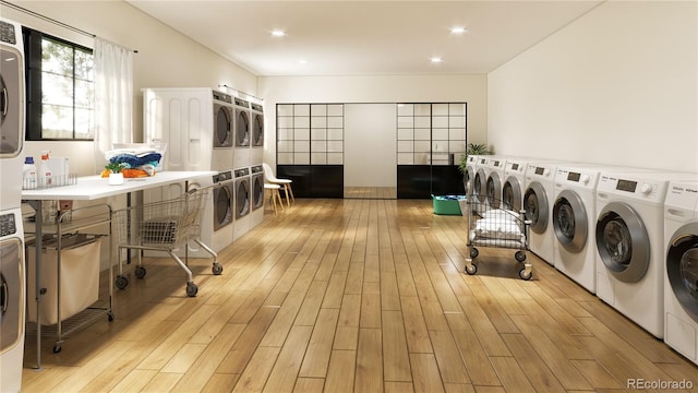 washroom with stacked washing maching and dryer, washing machine and dryer, and light hardwood / wood-style flooring