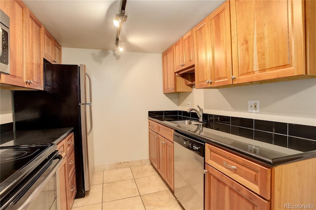 kitchen with light tile patterned flooring, track lighting, stainless steel appliances, and sink