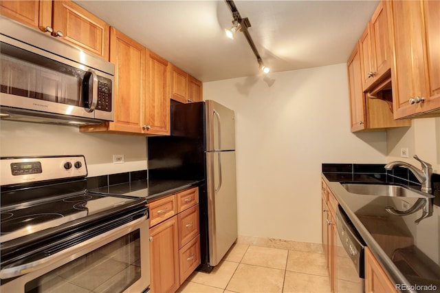 kitchen featuring light tile patterned flooring, track lighting, appliances with stainless steel finishes, and sink