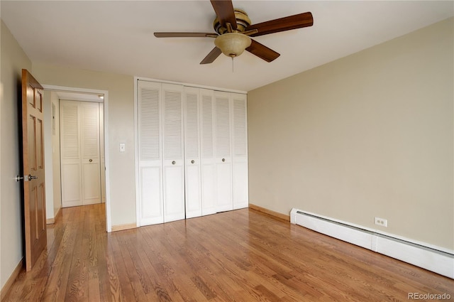 unfurnished bedroom with wood-type flooring, a closet, ceiling fan, and baseboard heating