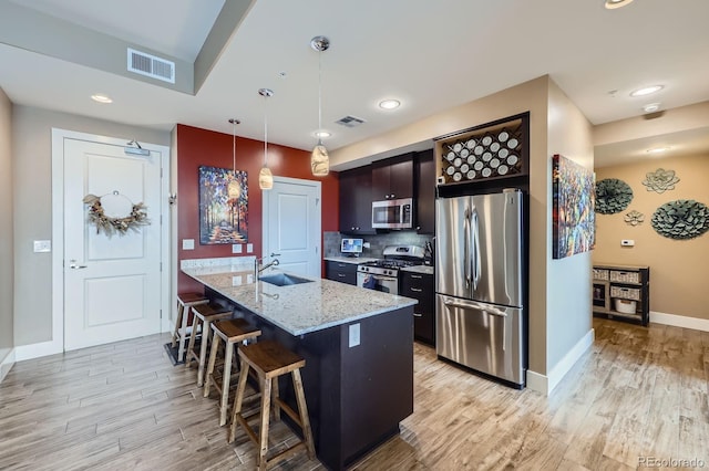 2001 Lincoln St Unit 2213, Denver, CO 80202 - kitchen featuring appliances with stainless steel finishes, a sink, a kitchen bar, light wood finished floors, and recessed lighting
