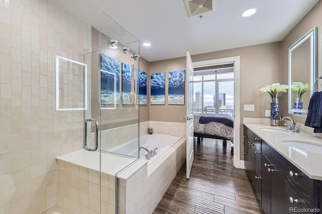 2001 Lincoln St Unit 2213, Denver, CO 80202 - ensuite bathroom featuring a stall shower, a bath, wood finished floors, double vanity, and recessed lighting