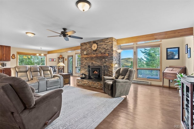 381 Highlands Dr, Bailey, CO 80421 - living room featuring a baseboard radiator, a wood stove, a ceiling fan, and wood finished floors