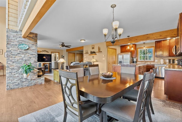 381 Highlands Dr, Bailey, CO 80421 - dining space with light wood finished floors, ceiling fan with notable chandelier, and beam ceiling