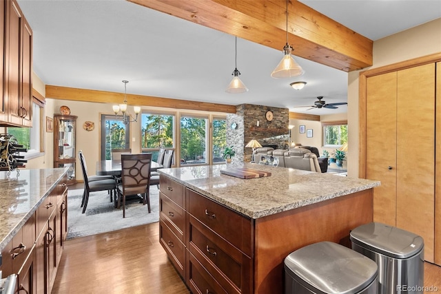 381 Highlands Dr, Bailey, CO 80421 - kitchen with light stone counters, wood finished floors, ceiling fan with notable chandelier, and a stone fireplace