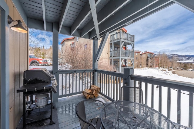 snow covered deck with grilling area, outdoor dining area, and a mountain view