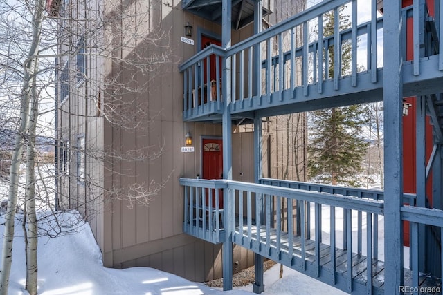 snow covered property entrance featuring a balcony
