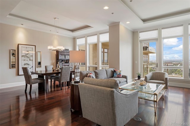 living room featuring a tray ceiling, a chandelier, dark wood-type flooring, and crown molding