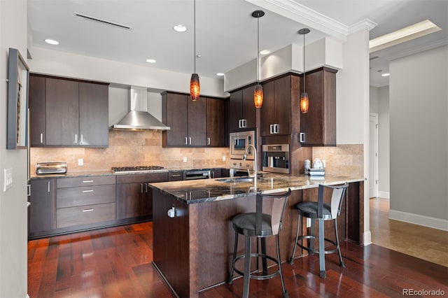 kitchen with dark brown cabinets, sink, wall chimney exhaust hood, stainless steel appliances, and dark hardwood / wood-style flooring