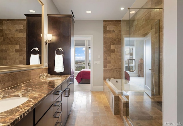 bathroom featuring tile walls, shower with separate bathtub, and vanity