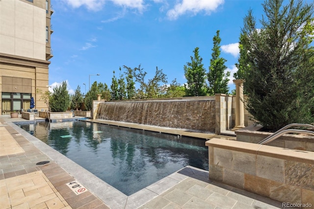 view of swimming pool with pool water feature and a patio area