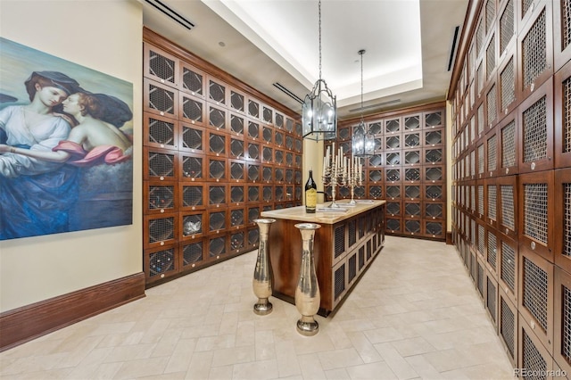 wine cellar featuring a tray ceiling and a chandelier