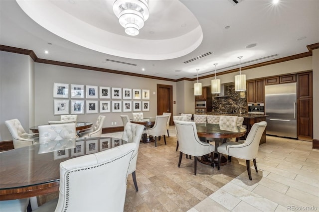 dining area with crown molding, a tray ceiling, and a chandelier