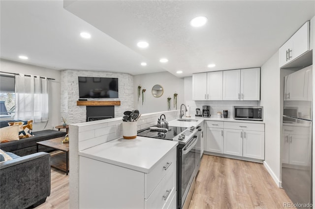 370 E Ln Bonte St Unit 502, Dillon, CO 80435 - kitchen with appliances with stainless steel finishes, a sink, open floor plan, a peninsula, and light wood-style floors