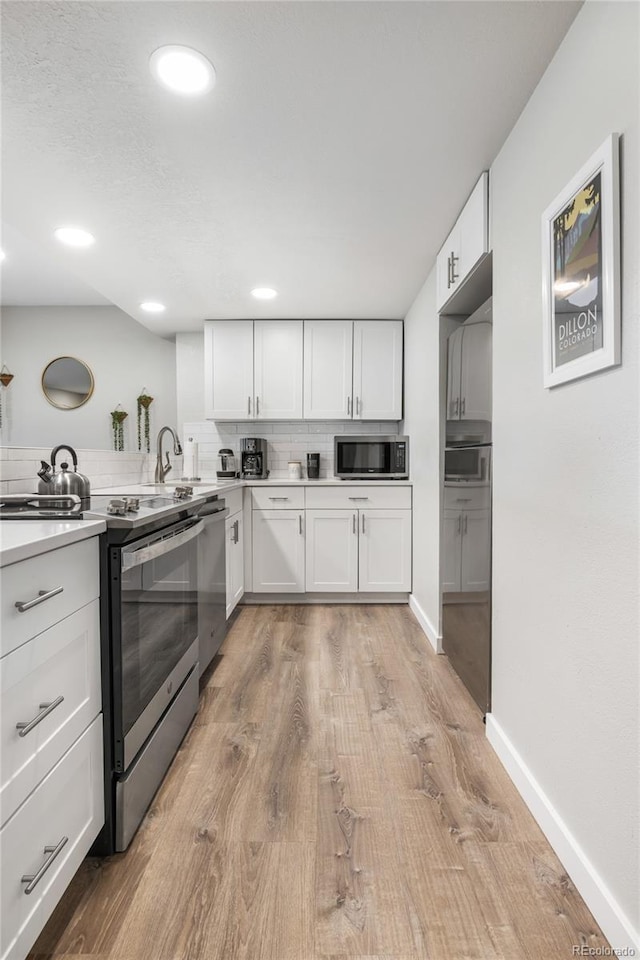 370 E Ln Bonte St Unit 502, Dillon, CO 80435 - kitchen with appliances with stainless steel finishes, light wood-type flooring, white cabinetry, light countertops, and baseboards