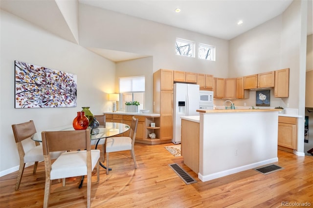 kitchen with visible vents, a towering ceiling, light brown cabinets, and white appliances