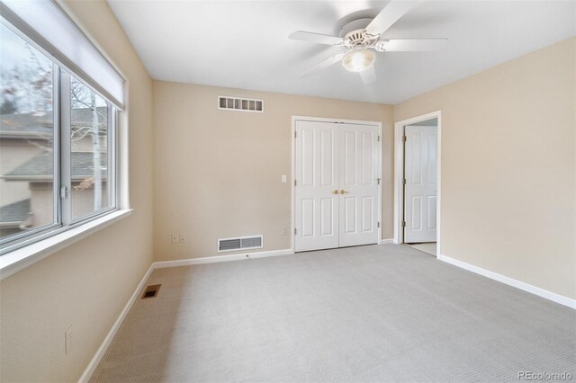 carpeted empty room with baseboards, visible vents, and ceiling fan