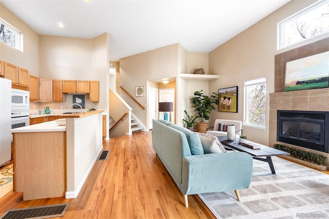 living area featuring light wood-type flooring, a high ceiling, and visible vents