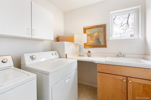 laundry area featuring light floors, cabinet space, washer and clothes dryer, and a sink