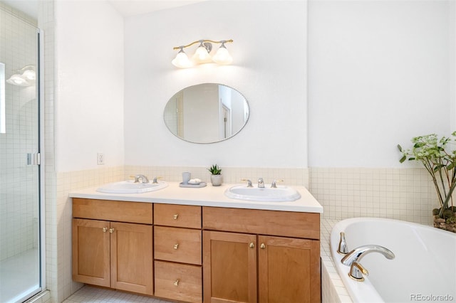 bathroom with double vanity, a garden tub, a stall shower, and a sink
