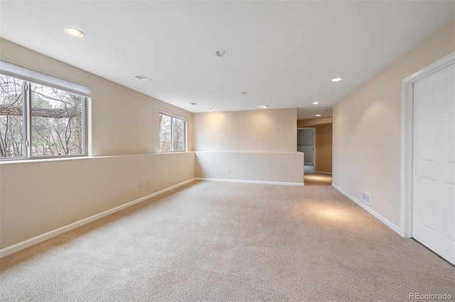 unfurnished room with baseboards, light carpet, visible vents, and recessed lighting
