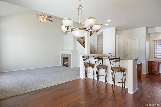 kitchen featuring pendant lighting, dark hardwood / wood-style flooring, a breakfast bar area, and a tile fireplace