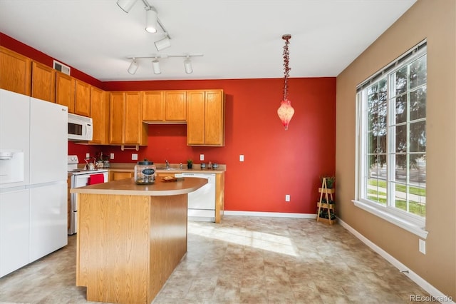 kitchen featuring pendant lighting, white appliances, a center island, and plenty of natural light