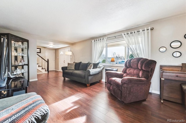living room featuring stairway, baseboards, wood-type flooring, and a textured ceiling