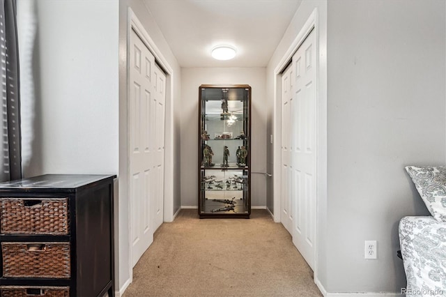 hallway featuring light carpet and baseboards
