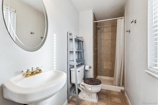 full bathroom featuring a sink, toilet, a stall shower, and tile patterned flooring